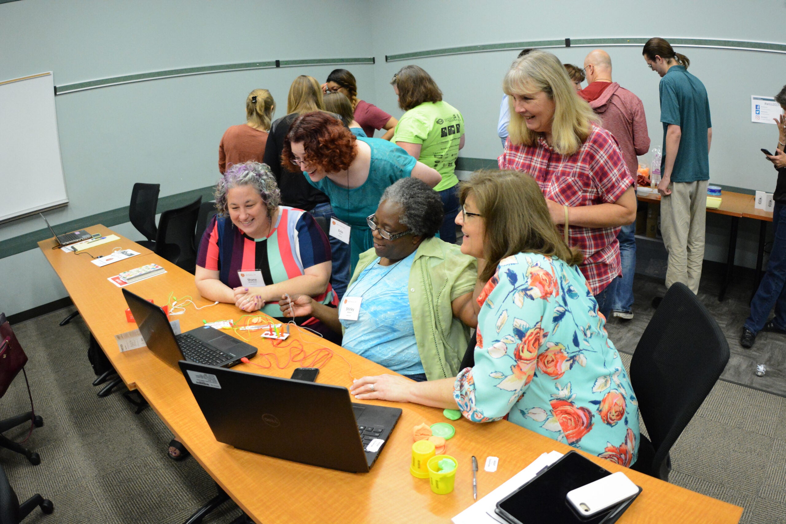 A group of teachers are huddled around looking at a screen