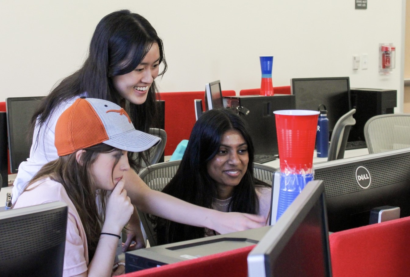 UTCS Summer Academies photo of 3 students engaging at a computer, pointing, and laughing